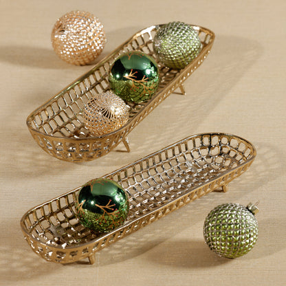 Decorative gold baskets with green ornaments on a beige surface