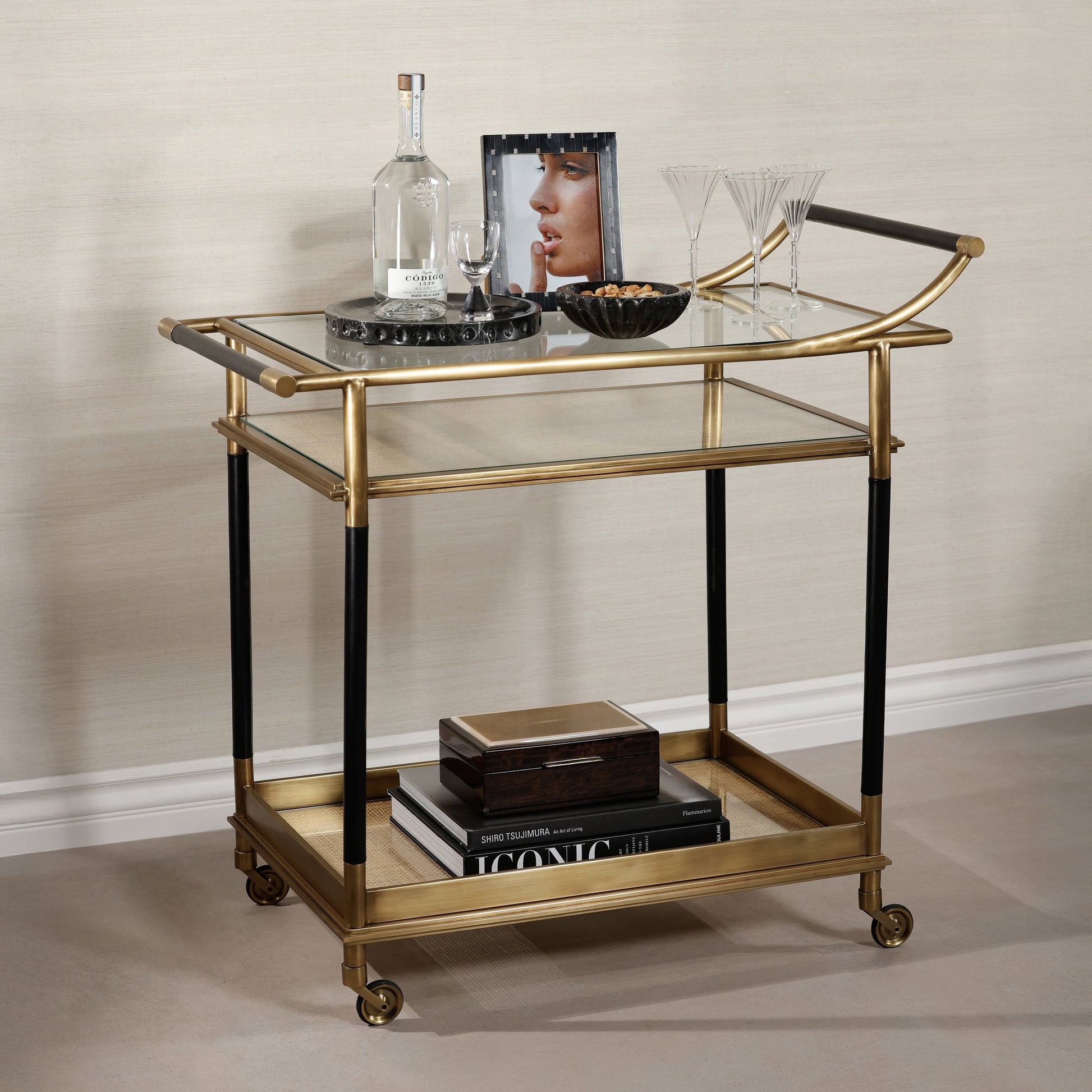 Gold and black serving cart with decorative items on a neutral background