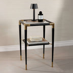 Peninsula Leather Side Table with glass top, black leather finish, and brass accents, styled with books and a lamp.