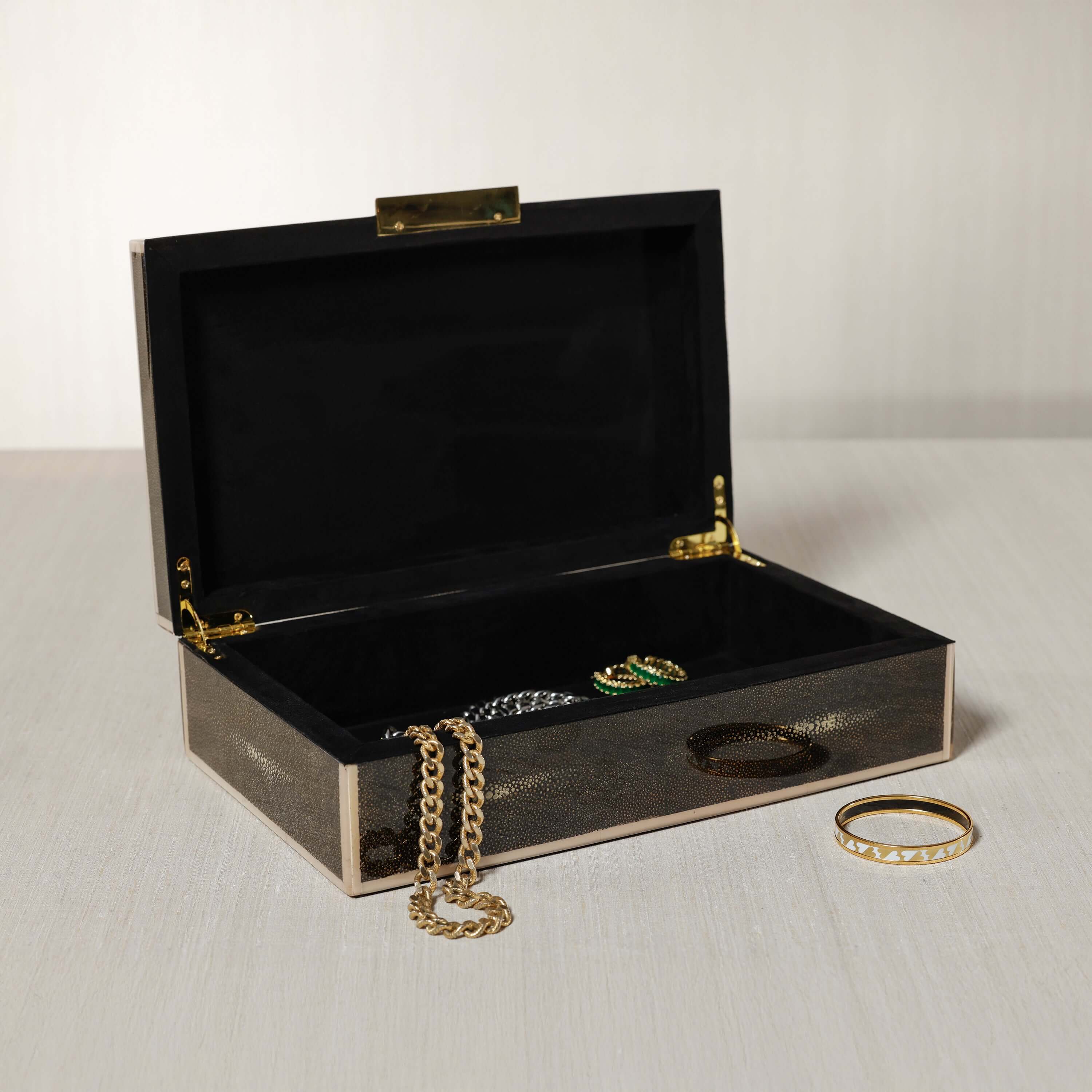 The Corinthia Box opened, showcasing jewelry with a luxurious deep charcoal shagreen texture.