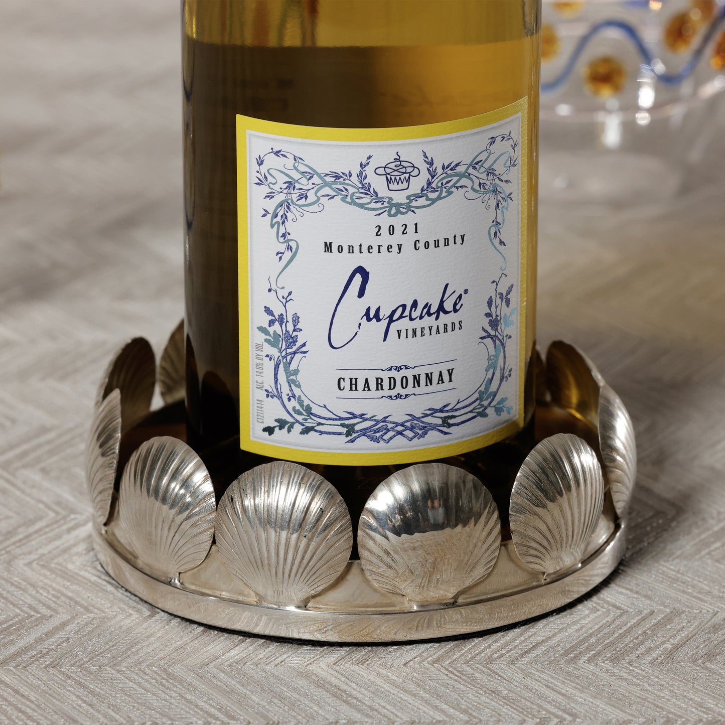 Bottle of Cupcake Vineyards Chardonnay on a decorative silver tray with a patterned background