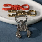 Lobster Bottle Opener in glossy red, polished gold, and silver on a plate, showcasing unique coastal design.