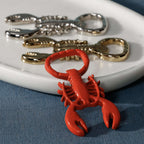 Lobster Bottle Opener in glossy red with silver and gold versions on a plate, showcasing coastal bar accessories.