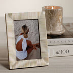 Nubia White Bone Ribbed Photo Frame showcasing a hand-carved design next to a candle and books.