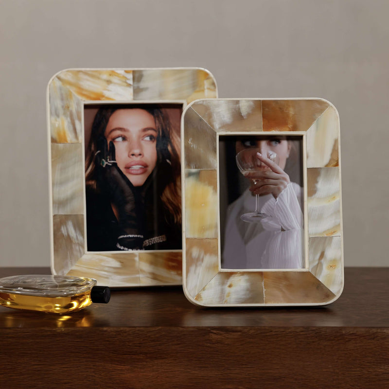 Two decorative photo frames with a woman's face on a wooden surface.