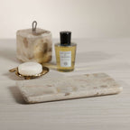 Crema Fossil Marble Bath Collection featuring a soap dish, lidded jar, and lotion bottle on a countertop.