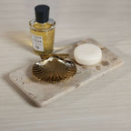 Crema Fossil Marble Bath Collection displayed with gold shell dish, soap, and fragrance bottle on a marble tray.
