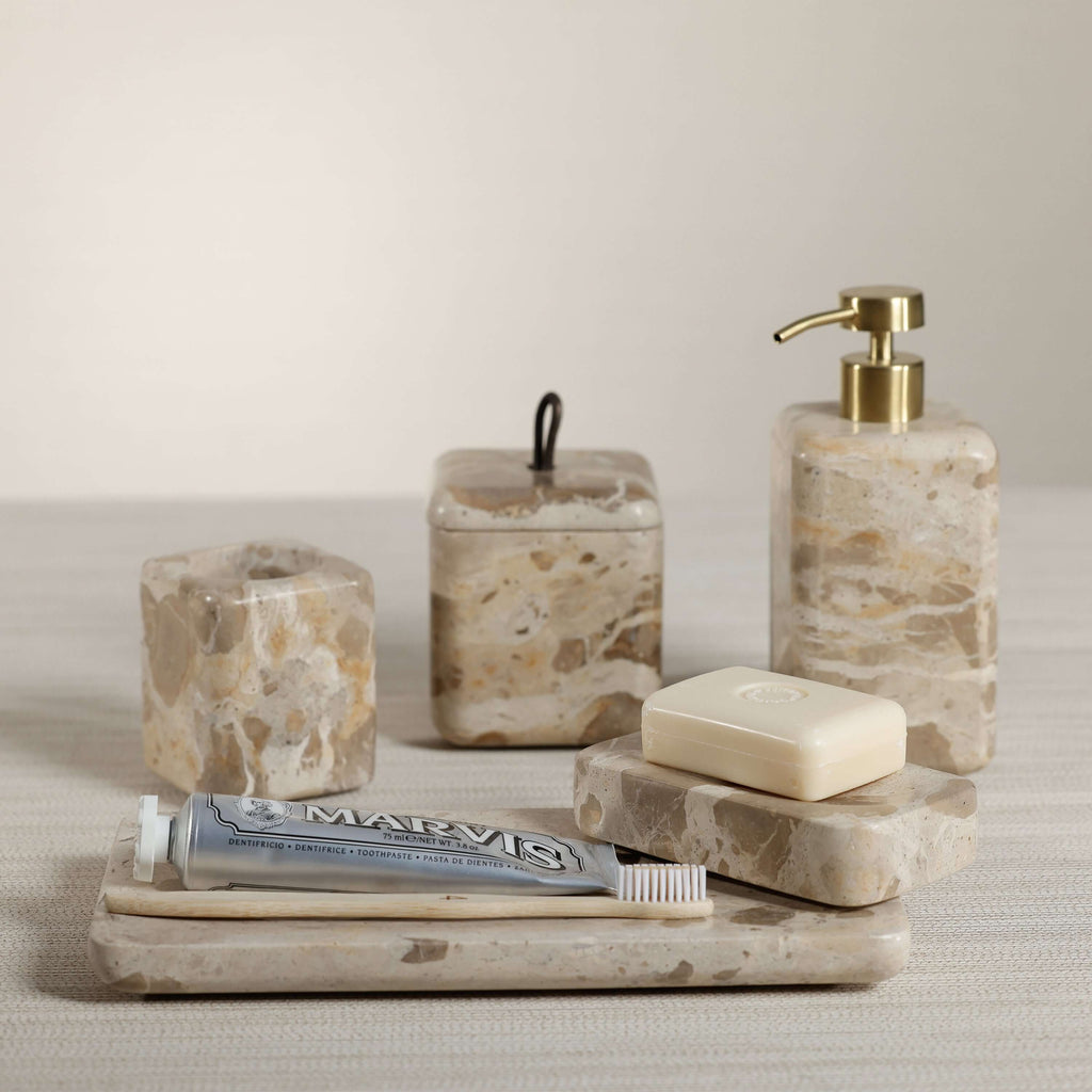 Crema Fossil Marble Bath Collection featuring a soap dispenser, lidded jar, and trays in natural marble.
