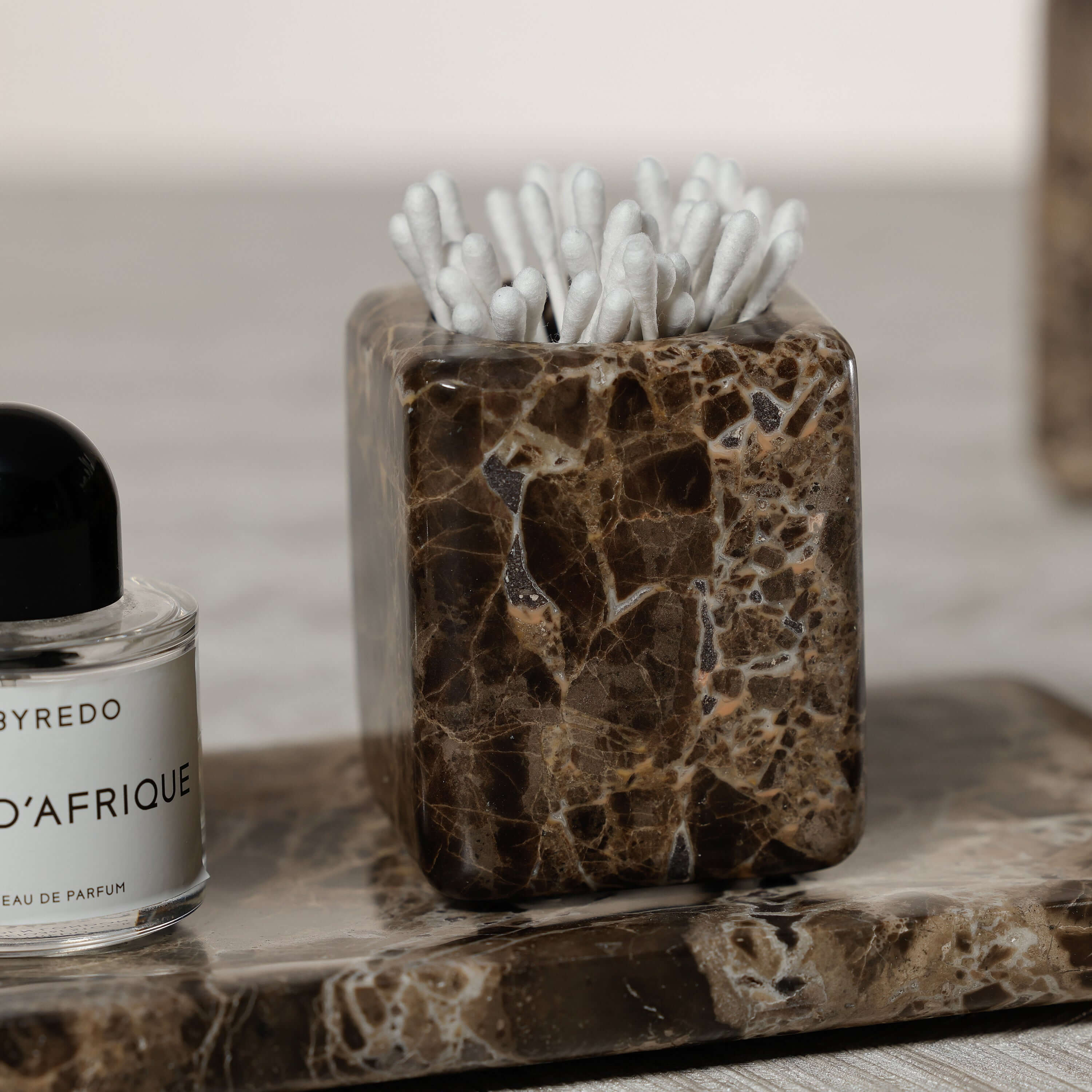 Marrón Emperador Marble Bath Collection cotton swab holder and perfume bottle on marble vanity tray.