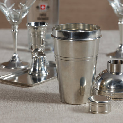 Metallic cocktail shaker and glasses on a textured surface