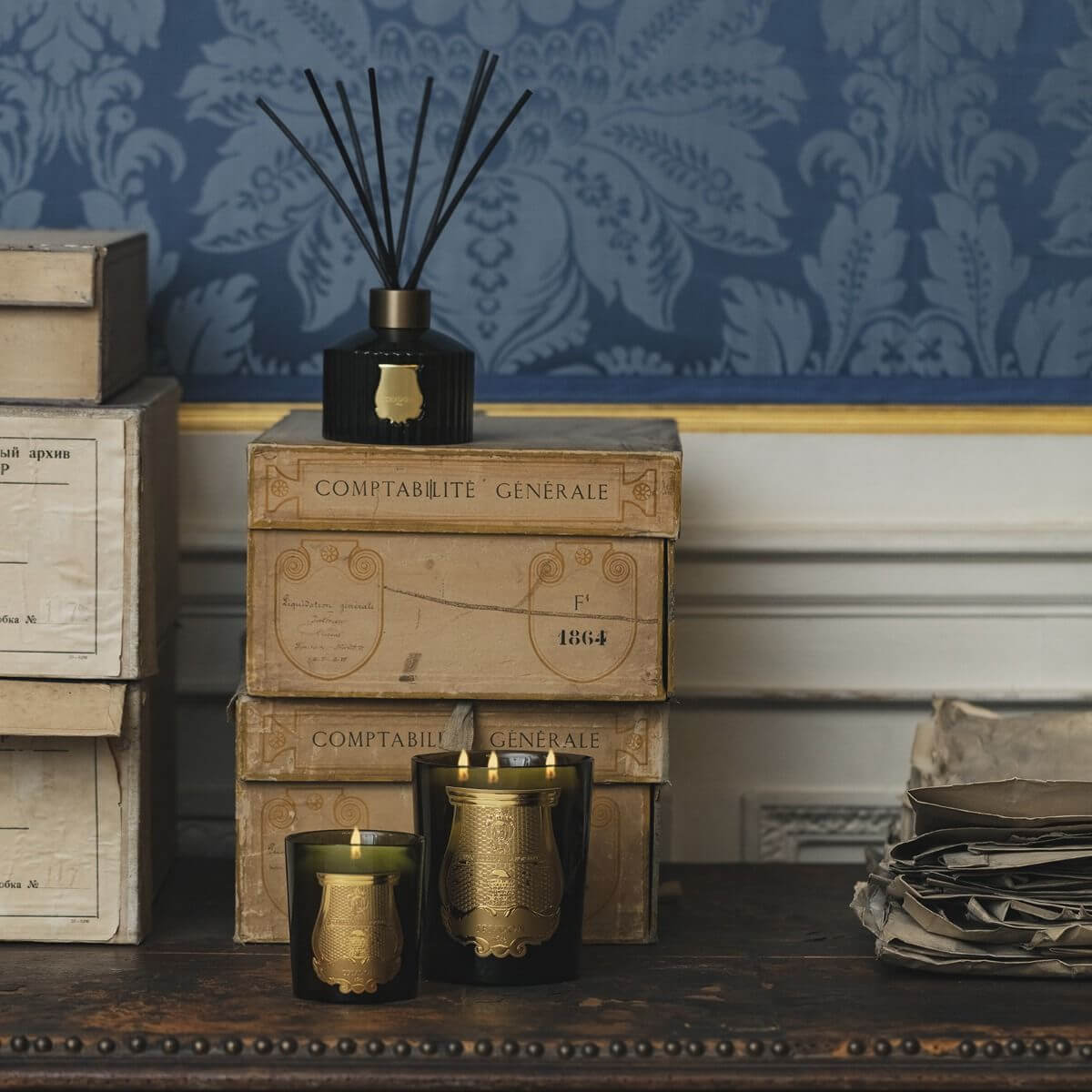 Abd El Kader Intermezzo Candle displayed on stacked vintage boxes with an elegant background.